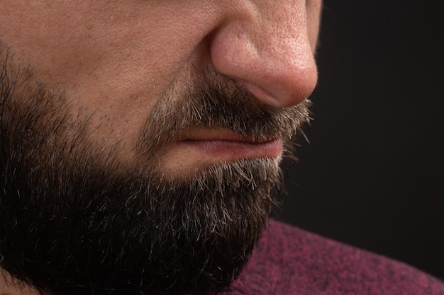 Wrinkled grimace of danger closeup on face and lips of young unrecognizable man with black beard and...