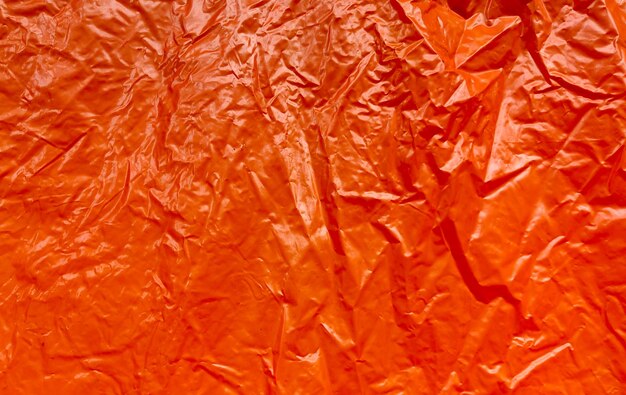 Photo wrinkled orange glossy paper as a background texture