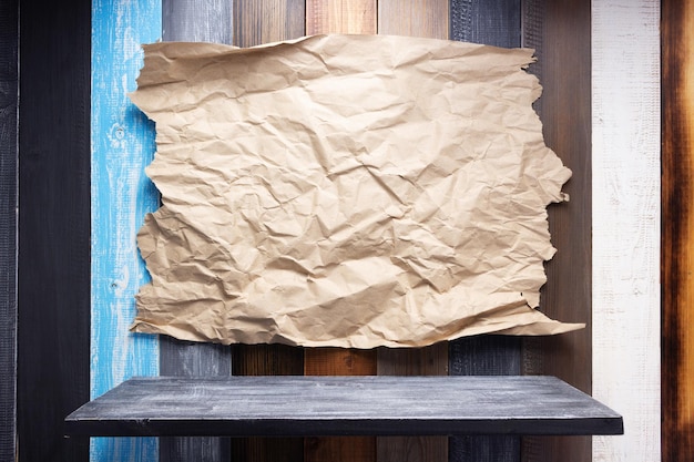 Wrinkled paper at wooden board background