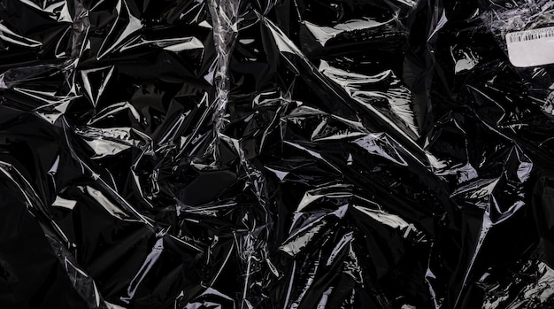 黒い背景のプラスチックの包み込みのテクスチャー 透明なセロファンのパッケージの壁紙