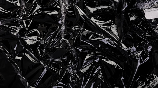 Photo wrinkled plastic wrap texture on a black background transparent cellophane package wallpaper