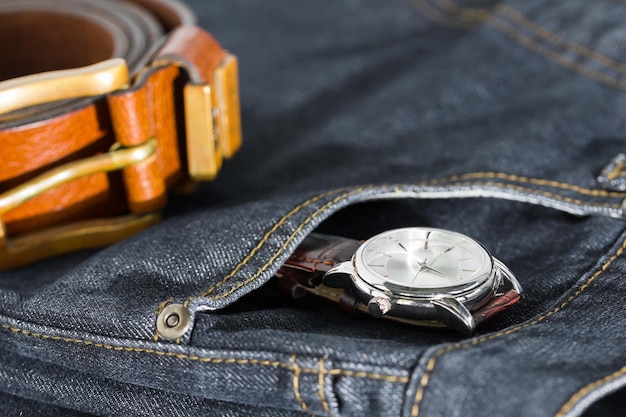 Wrist watch and leather belt on jeans