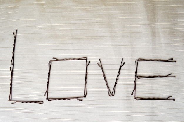 Фото Напишите любовь, написанную шпильками на бежевом фоне. слово «любовь»