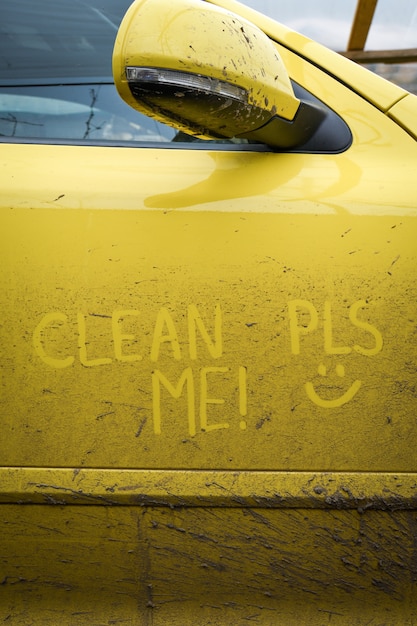 Write the words inscription text " clean me " on the very dirty surface of the car. Concept car wash.