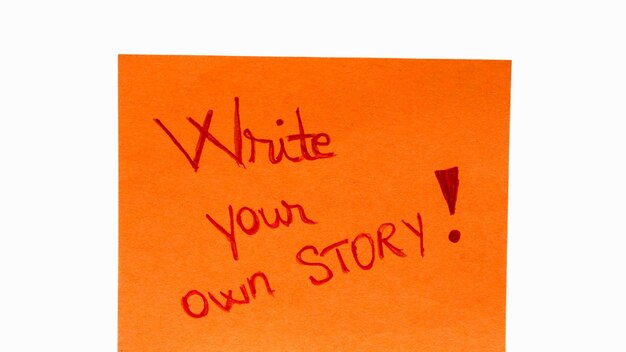 コピースペースのある黄色い紙に独自のストーリーを手書きのテキストをクローズアップして書きます