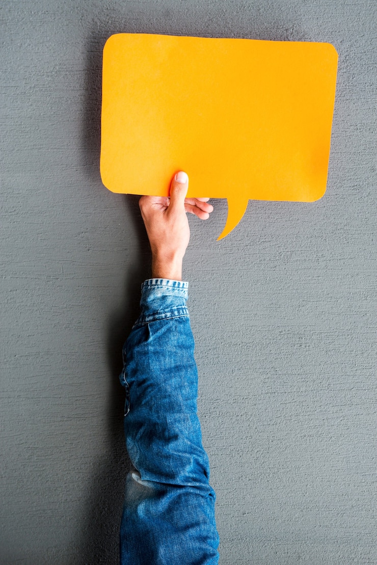 Photo write your thoughts. close-up of man stretching out empty speech bubble against grey background