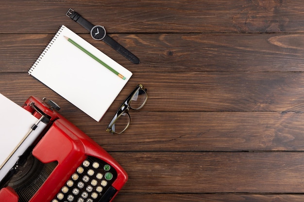 Writer or journalist workplace vintage red typewriter glasess and notepad on the wooden desk