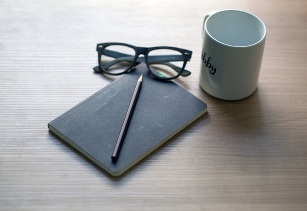 Writer's career on the desk with a white coffee mug, pencil and glasses book
