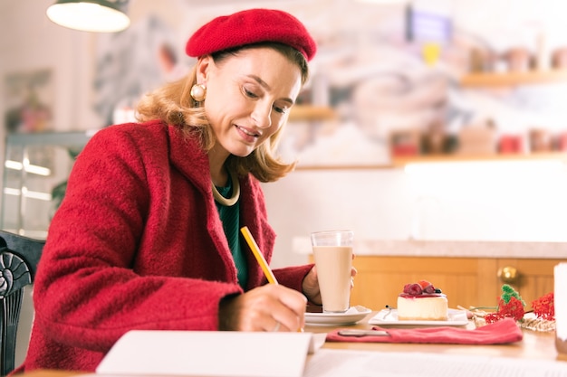 Writer with pencil. French writer wearing red beret and red coat holding pencil while making some notes