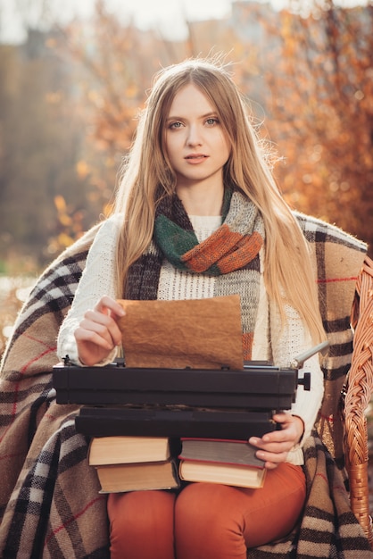 Lavoro della donna dello scrittore sulla vecchia macchina da scrivere nel parco di autunno