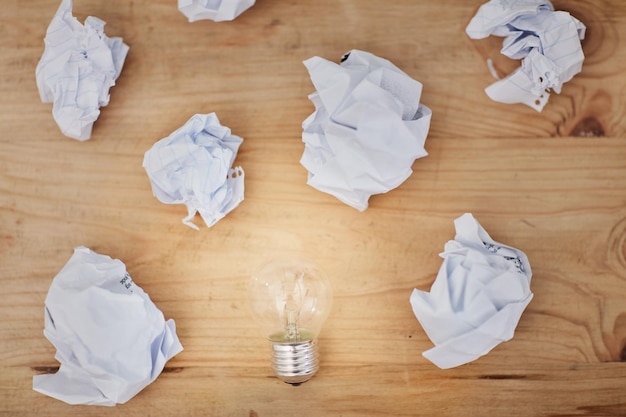 Writers block High angle shot of a lightbulb surrounded by crumpled pieces of paper on a desk