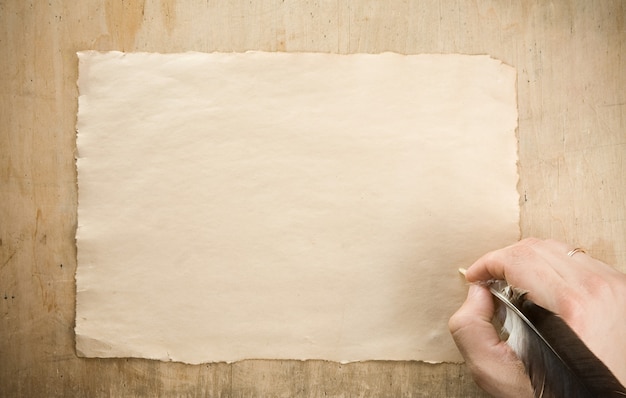 Writing hand with pen feather on wood table