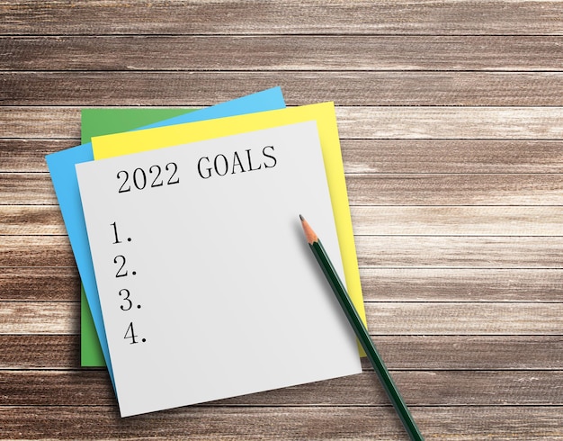 Photo writing note showing 2022 goals on wood table background top view with copy space