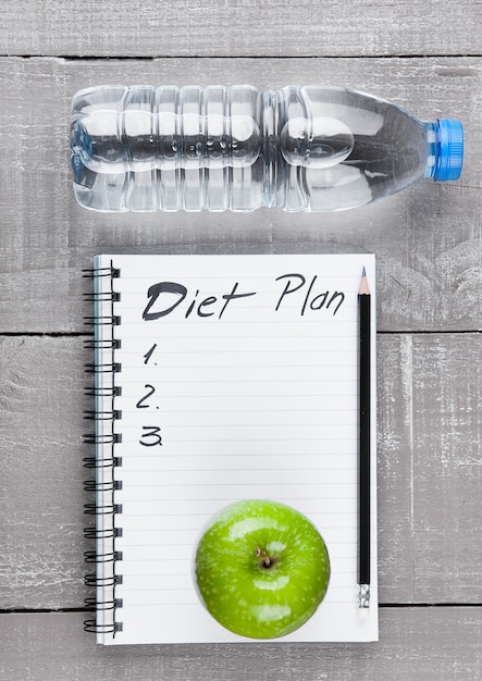 Writing pad with apples and water as diet  idea on wooden board