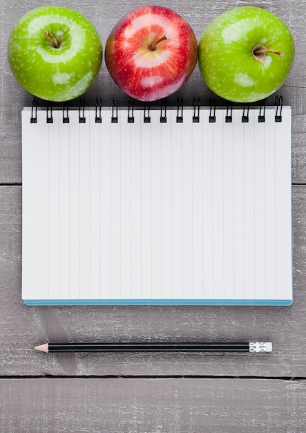 Photo writing pad with healthy apples as diet plan idea on wooden board