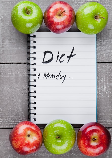 Writing pad with healthy apples as diet plan idea on wooden board