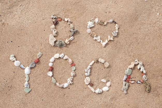 Writing with shells text Yoga on beach