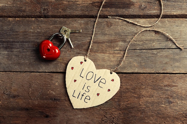 Written message with decorative heart on wooden table close up