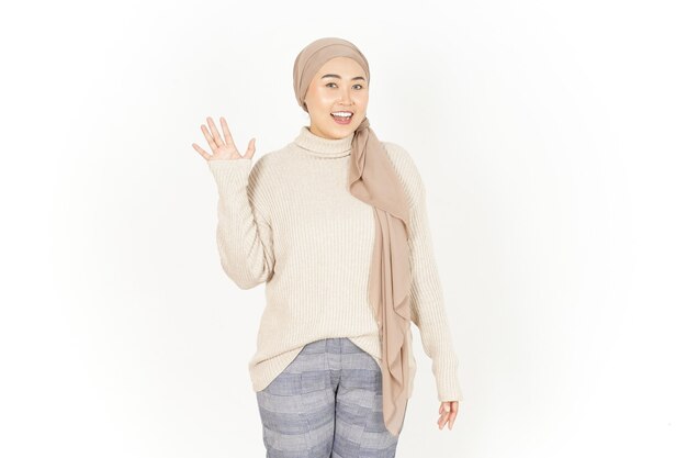 Wuivende hand groet van mooie Aziatische vrouw die hijab draagt geïsoleerd op een witte achtergrond