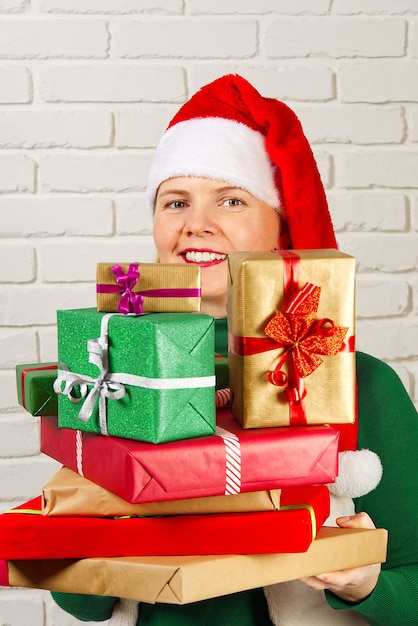 Foto wwoman in rode hoed met veel kerstcadeaus. vrouw met veel dozen met geschenken