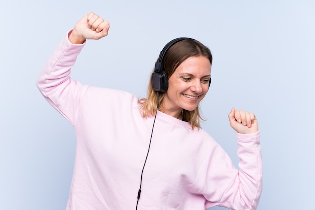 Wwoman listening music over isolated blue wall