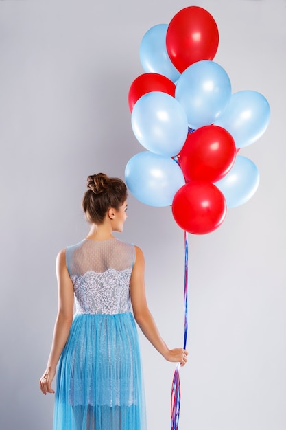 Wwoman wearing beautiful dress with a lot of colorful balloons