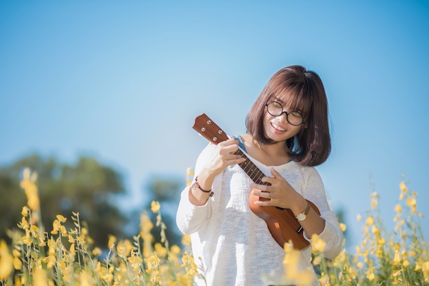 &#xA;Young woman playing on Ukulele on Sunhemp background