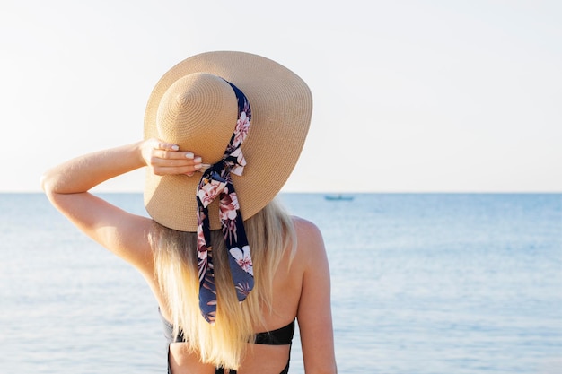 XAGirl in a hat and swimsuit on the background of the sea Back view