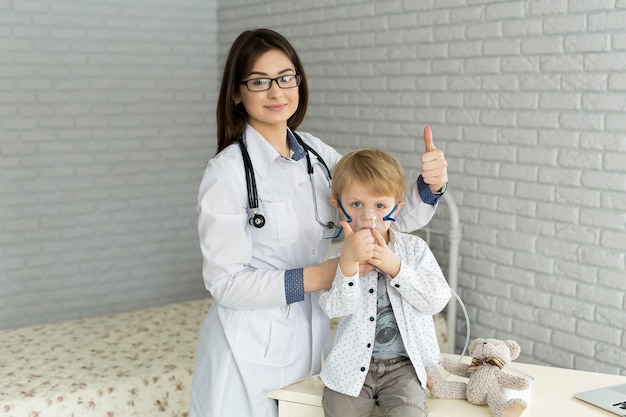 사진 천식 흡입이 있는 어린 소년에게 약물 흡입 치료를 적용하는 xamedical 의사
