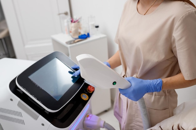 XAPProfessional косметолог проводит кавитационное омоложение кожи в клинике Радиоволновой лифтинг Косметолог держит ультразвуковое устройство для процедуры подтяжки лица
