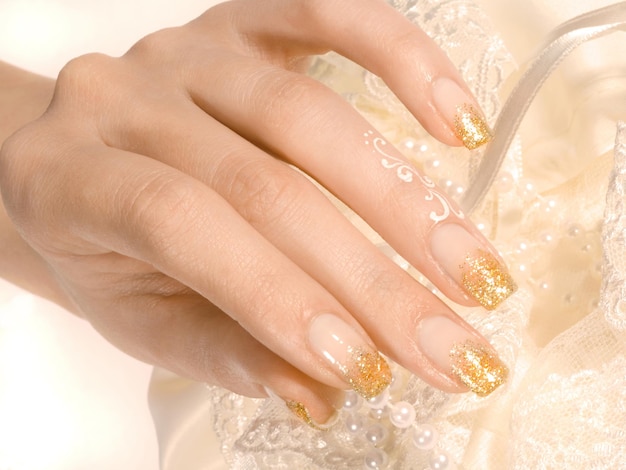 Xasluit shot van de hand van de vrouw met gouden manicure op gele xabackground