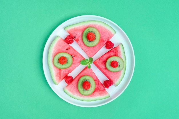 접시에 딸기와 과일이 있는 Xa수박 녹색 배경 상단 보기 근접 촬영에 있는 접시에 딸기와 과일이 있는 수박