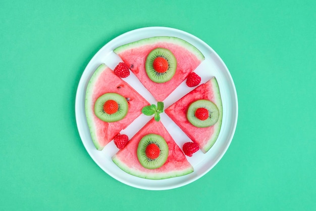 XAWatermelon with berries and fruits in a plate xAWatermelon with berries and fruits in a plate on a green background top view closeup