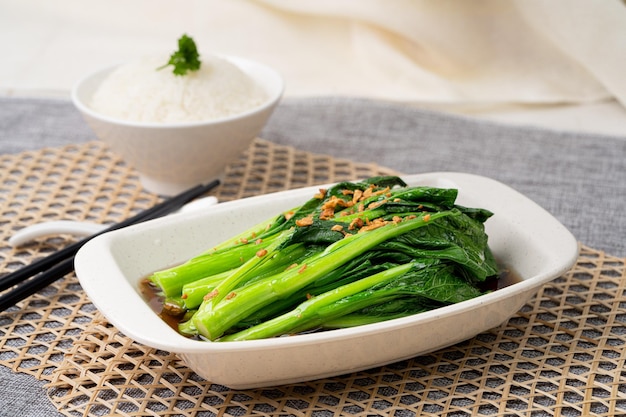 XIAO BAI CAI With GARLIC OYSTER SAUCE with chopsticks served in dish isolated on table top view of singapore food