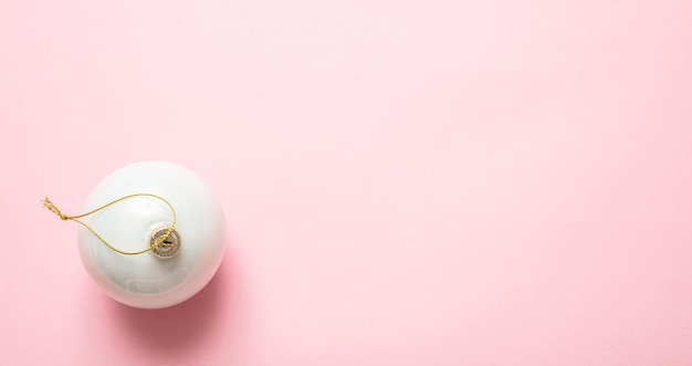 Xmas bauble white color against pink background high angle