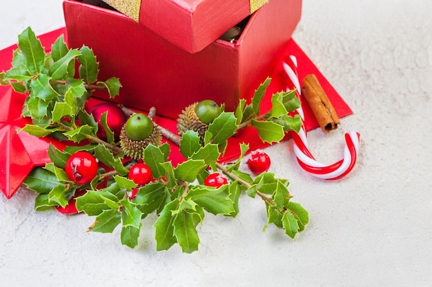 Concetto di natale con foglie di agrifoglio invernale, bacche rosse e regalo