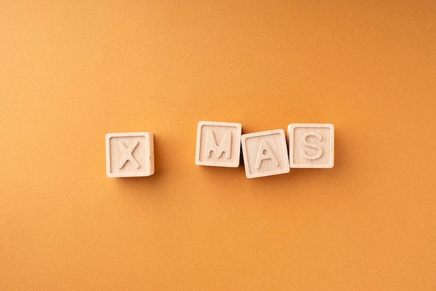 Xmas is geschreven op de houten kubussen houten kubussen met letters op een oranje achtergrond nieuwjaarskaart