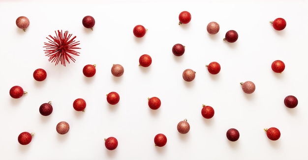 Xmas red shades balls flat lay on white background Small baubles scattered on card top view