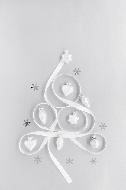 Foto albero di natale fatto di nastro bianco, decorato con coriandoli fiocco di neve. lay piatto