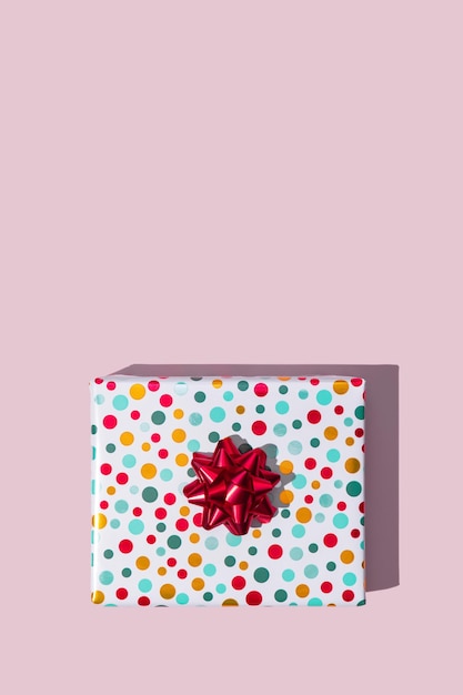 Xmas wenskaart Geschenkdoos met rode strik op roze achtergrond bovenaanzicht Kopieer ruimte Mockup Plat leggen