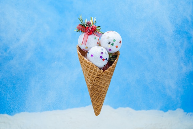Xmas white shiny ice cream balls in waffle cone on blue