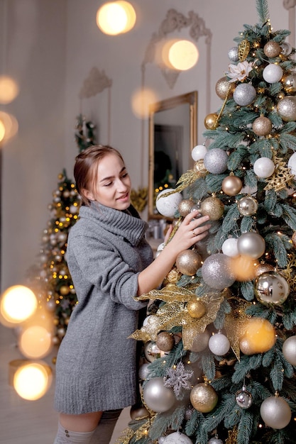 Xmas wintervakantie en mensenconcept gelukkige jonge vrouw die kerstboom thuis versiert