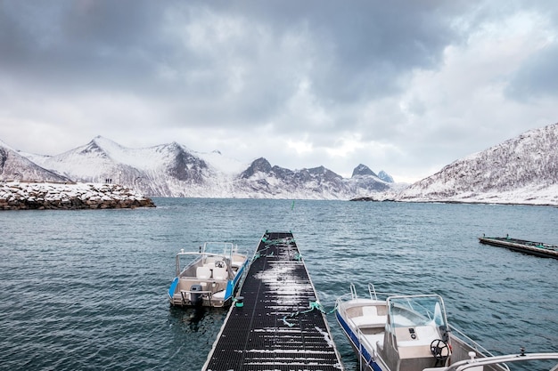 Yacht moored with jetty in surrounded mountain on cloudy sky