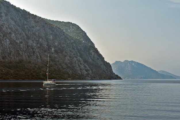 Yacht sails on the sea along the mountains