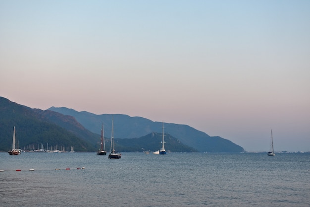 Yacht sails on the sea along the mountains