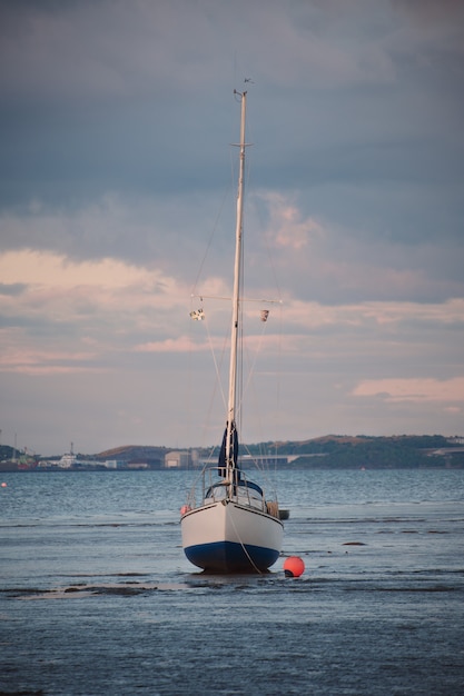 写真 スコットランドのサンセットでフォース湾を背景に浅瀬に立ってヨット