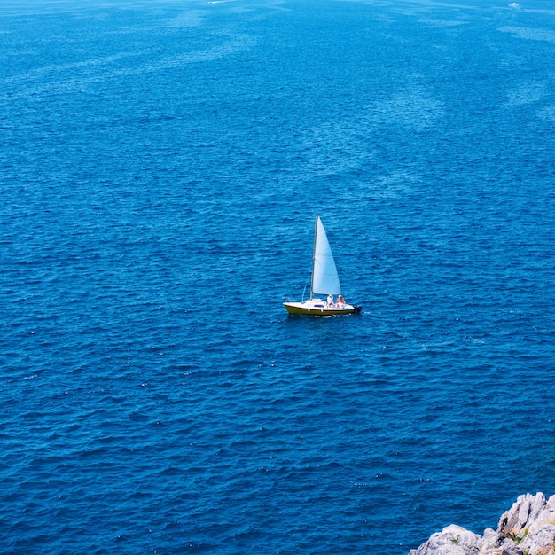 Yacht wirh sail in the sea near coast on the summer day - Minimalistic seascape