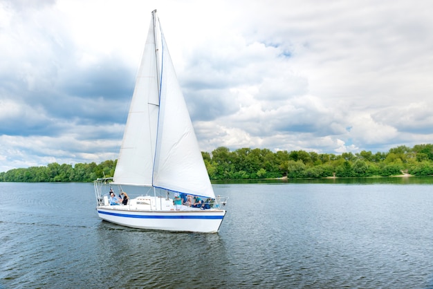 Yacht with white sail on the blue water