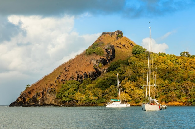 Yachts anchored at the Pigeon Island with fort ruin on the rock Rodney bay Saint Lucia Caribbean sea