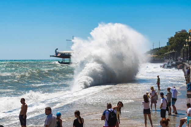 ヤルタ、クリミア-2018年8月10日：ヤルタの嵐、堤防の近くで巨大な波を壊します。嵐の海。荒れ狂う黒海。都市の堤防に対する大きな海の波のしぶき。危険で強力な自然の概念。